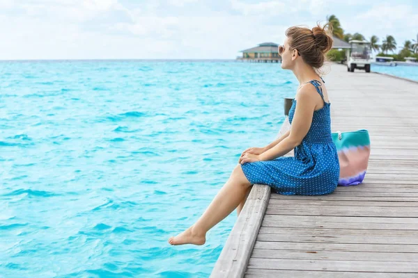 Gyönyörű fiatal nő ül a ponton tengeren resort — Stock Fotó