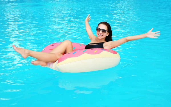 Belle jeune femme sur beignet gonflable dans la piscine — Photo