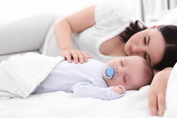 Wanita muda dengan bayi lucu tidur di tempat tidur — Stok Foto