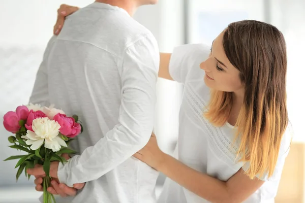 Young man hiding bouquet of flowers for his girlfriend behind back — Stock Photo, Image