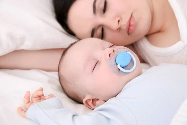 Cute little baby with mother sleeping on bed Stock Picture