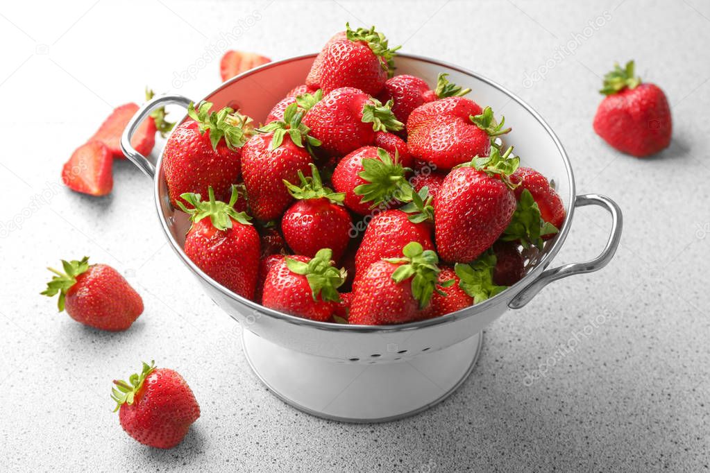 Collander with delicious strawberry on table