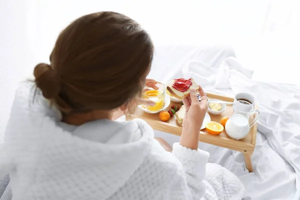 Νεαρή όμορφη γυναίκα παίρνει πρωινό στο κρεβάτι — Φωτογραφία Αρχείου