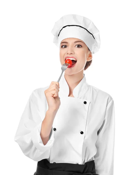 Jovem chef comendo tomate no fundo branco — Fotografia de Stock