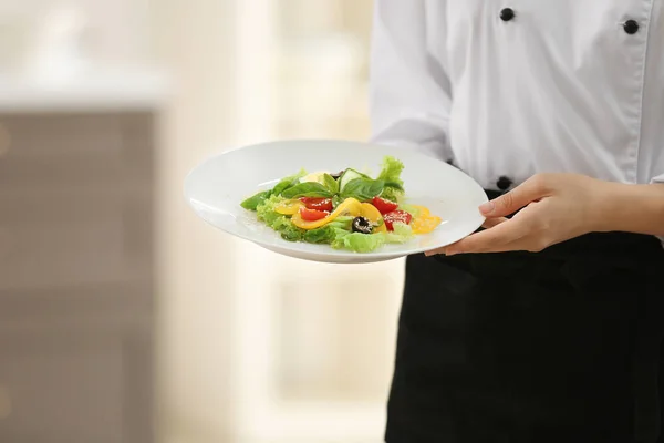 Joven cocinera con sabrosa ensalada en la cocina —  Fotos de Stock