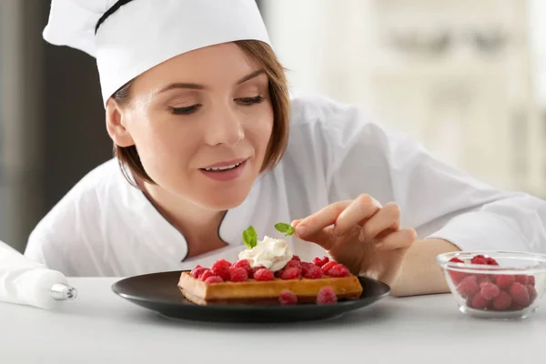 Жіночий шеф-кухар прикрашає десерт — стокове фото