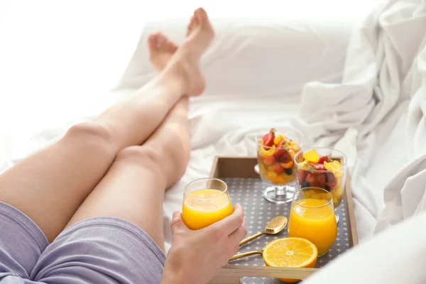 Jovem mulher tendo saboroso café da manhã na cama — Fotografia de Stock