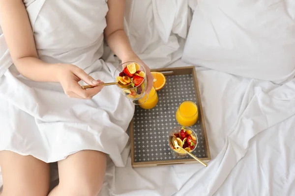Ung kvinna med välsmakande frukost på säng — Stockfoto