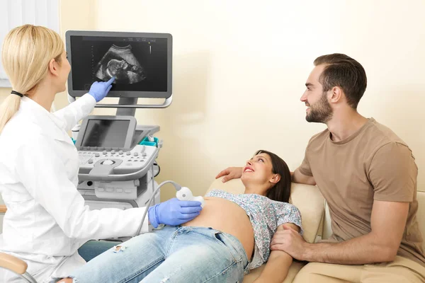 Pareja embarazada joven sometida a ecografía en clínica — Foto de Stock