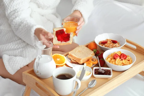 Junge schöne Frau frühstückt auf dem Bett — Stockfoto