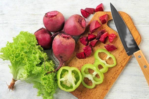 Frische junge Rüben und Paprika mit Salatblättern auf Holzgrund — Stockfoto