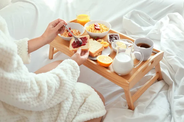 Νεαρή όμορφη γυναίκα παίρνει πρωινό στο κρεβάτι — Φωτογραφία Αρχείου