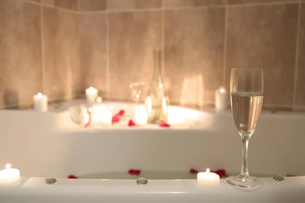 Glas met alcoholische drank en kaarsen voor de romantische datum op Bad lip — Stockfoto
