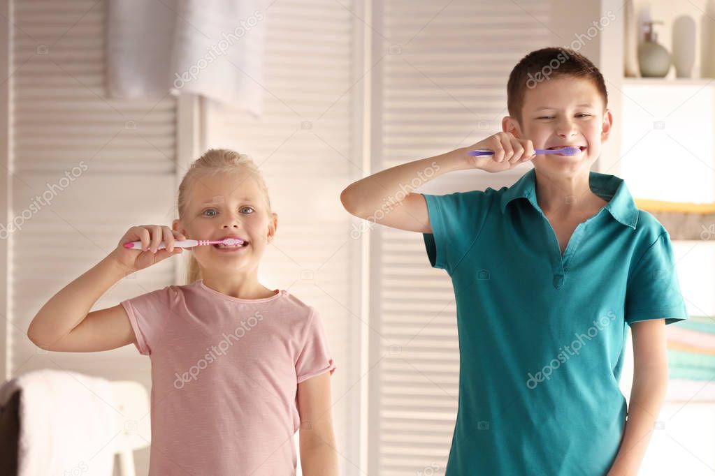 Cute little children cleaning teeth at home