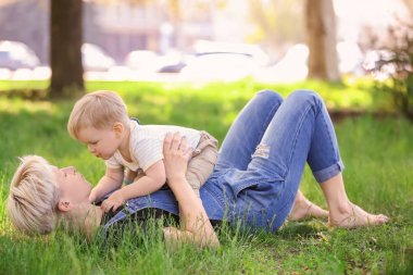 Anne ve şirin bebek çocuk parkı yeşil çim üzerinde yalan