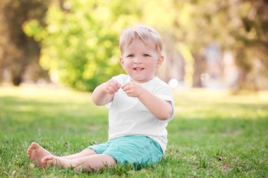 Şirin bebek çocuk parkı yeşil çimenlerin üzerinde oturan