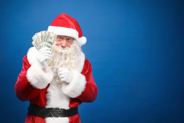 Weihnachtsmann hält Geld auf farbigem Hintergrund — Stockfoto