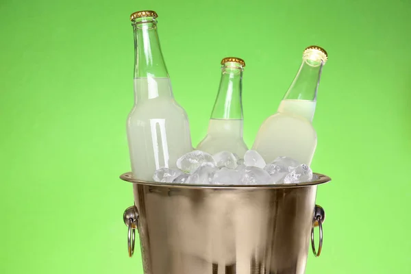 Бутылки лимонада в ведре со льдом на зеленом фоне — стоковое фото