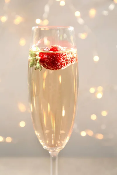 Glas utsökt vin med jordgubbe mot oskärpa lampor — Stockfoto