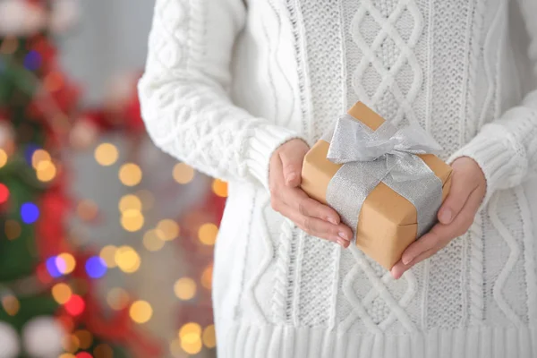 Mujer sosteniendo caja de regalo contra luces borrosas de Navidad —  Fotos de Stock