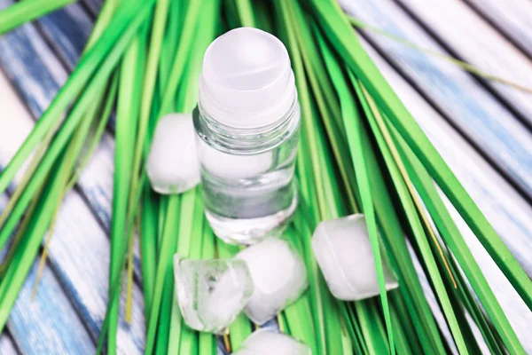 Deodorant for men, green leaves and ice cubes on wooden background