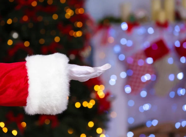 Santa Claus hand tegen wazig Kerstverlichting — Stockfoto