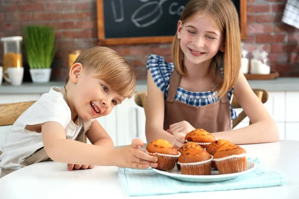 男の子と女の子のキッチンでおいしいマフィンを食べるします。料理クラスの概念 — ストック写真