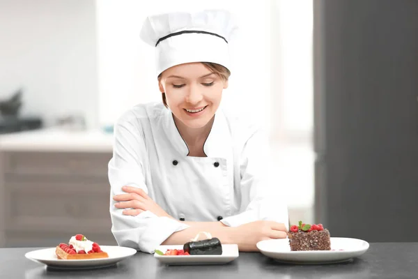 Female chef with tasty desserts in kitchen