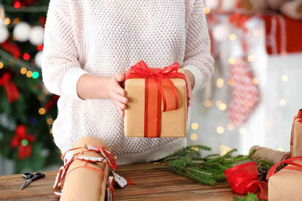 Femme tenant boîte cadeau contre les lumières de Noël floues — Photo