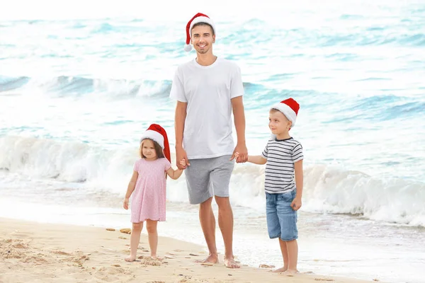 Padre joven con lindos hijos en la playa. Concepto de Navidad —  Fotos de Stock