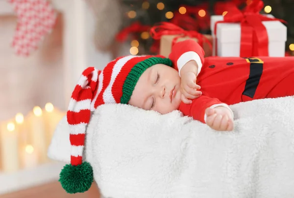Mignon petit bébé en costume de Père Noël dormir sur fond flou lumières de Noël — Photo