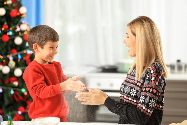 Jonge vrouw voorbereiding van kerstkoekjes met zoontje in keuken — Stockfoto