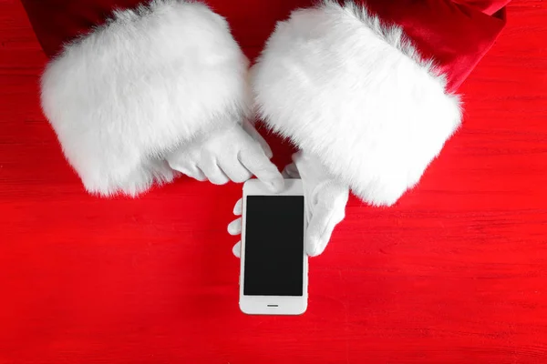 Santa Claus holding mobile phone on red background — Stock Photo, Image