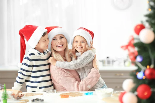 Mujer joven preparando galletas de Navidad con niños pequeños en la cocina — Foto de Stock