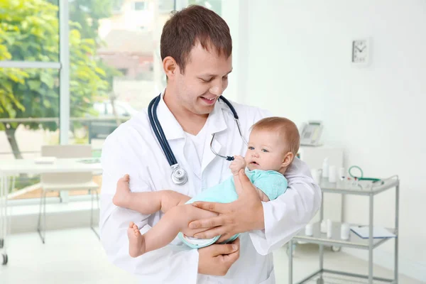 Masculino pediatra segurando bonito bebê menina dentro de casa — Fotografia de Stock