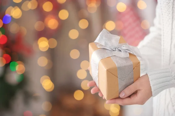 Mujer sosteniendo caja de regalo contra luces borrosas de Navidad —  Fotos de Stock