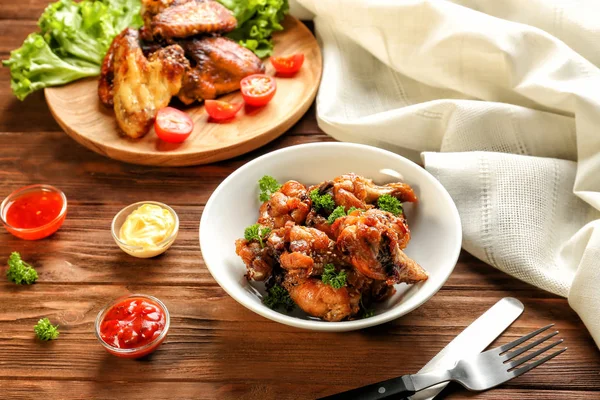 Tasty chicken and small bowls with sauces on wooden table — Stock Photo, Image