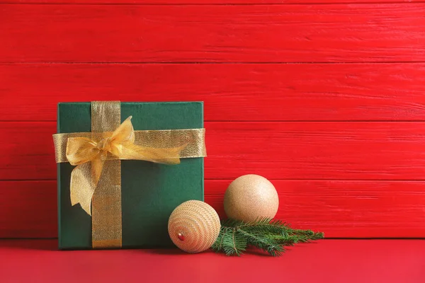 Gift box and Christmas decorations on table against color wall — Stock Photo, Image
