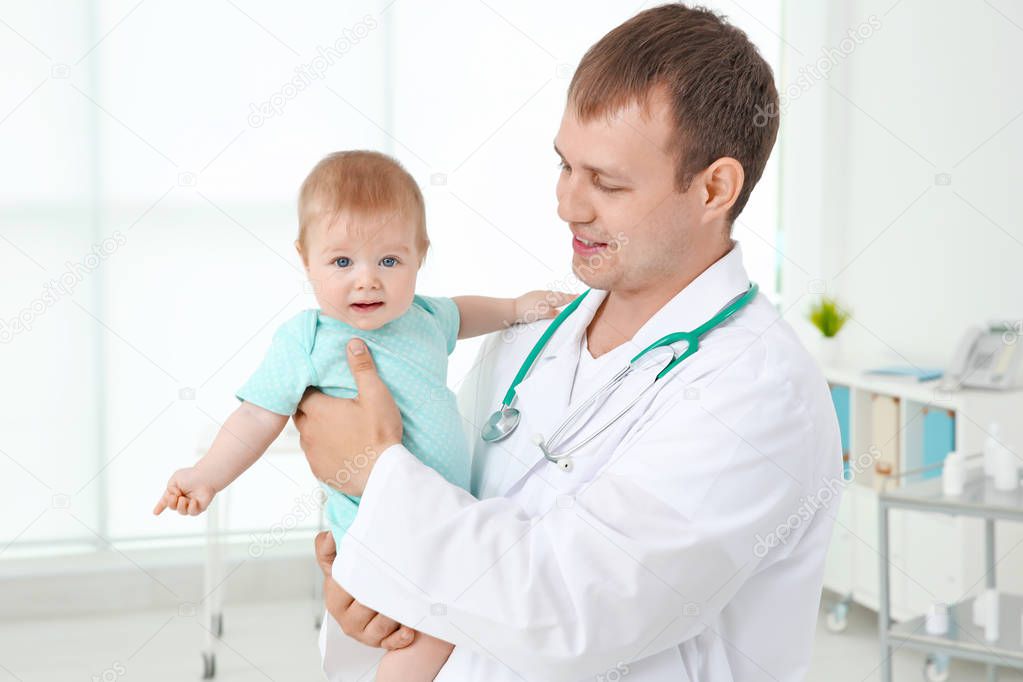 Male pediatrician holding beautiful baby girl indoors