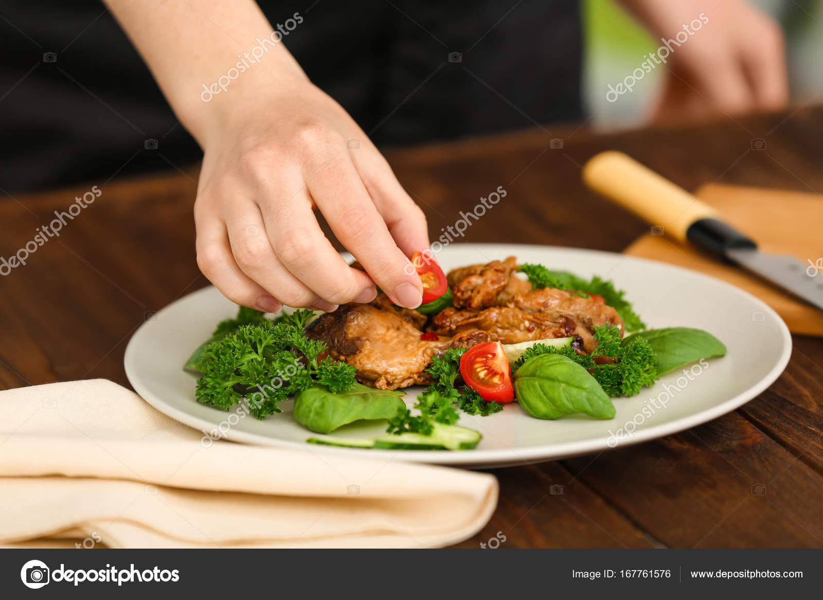 Woman Decorating Chicken Dish With Vegetables In Kitchen Stock