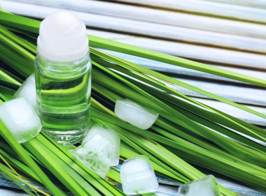 Deodorant erkek, yeşil yaprakları ve ahşap arka plan buz küpleri için