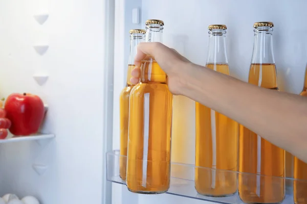 Mulher tomando uma garrafa de limonada de geladeira aberta — Fotografia de Stock