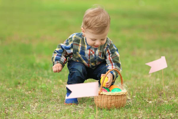 Anak kecil yang lucu dengan keranjang di rumput hijau. Konsep berburu telur Paskah — Stok Foto