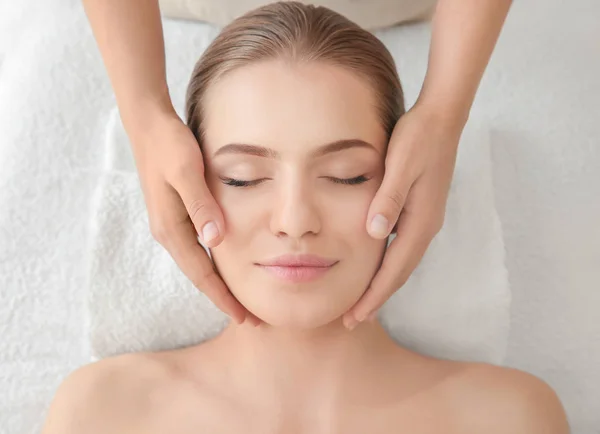 Mujer joven disfrutando del masaje facial en el salón de spa —  Fotos de Stock