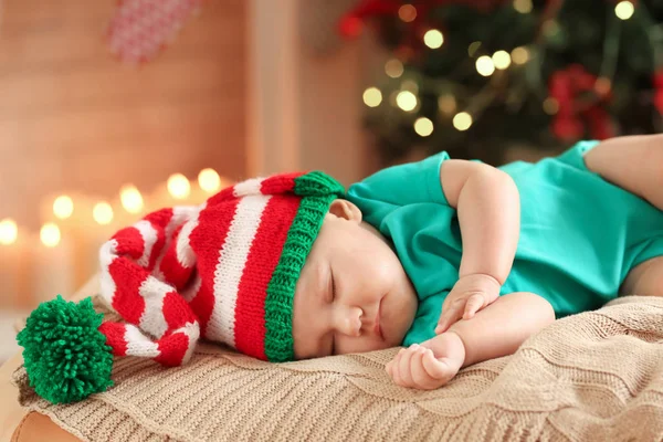 Söt liten bebis sover mot suddig jul ljus bakgrund — Stockfoto