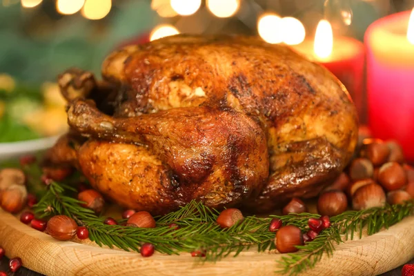 Composition with whole roasted turkey, coniferous branches and hazelnuts against defocused lights