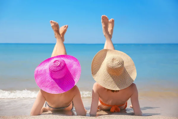 Jeunes femmes en chapeaux sur la plage de la mer — Photo