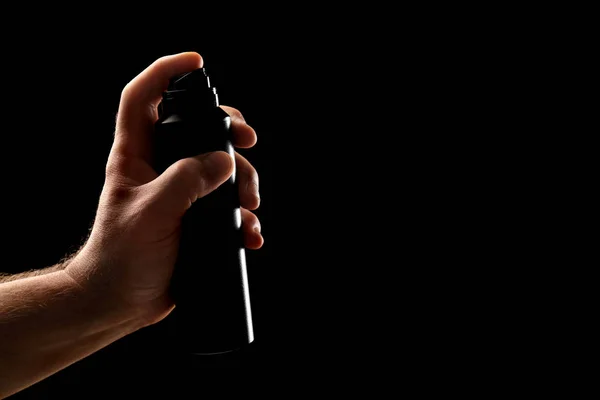 Hand of man holding deodorant on dark background — Stock Photo, Image