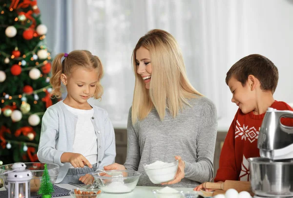 Jonge vrouw voorbereiding van kerstkoekjes met kleine kinderen in de keuken — Stockfoto