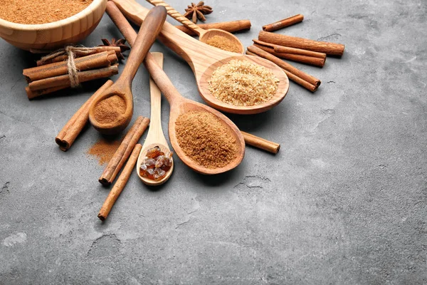 Kompozycja z cynamonu, cukier i proszek w drewniane łyżki na szarym tle — Zdjęcie stockowe